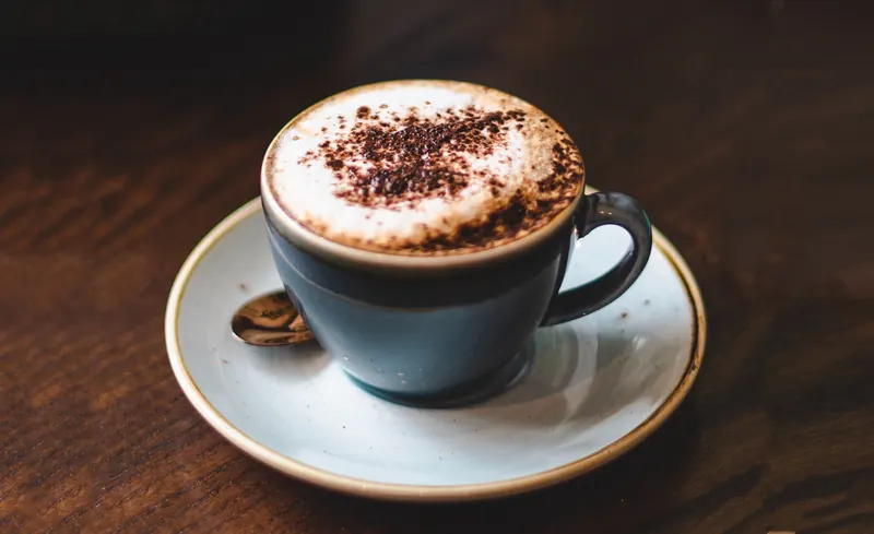 A cappuccino dusted with chocolate on a saucer