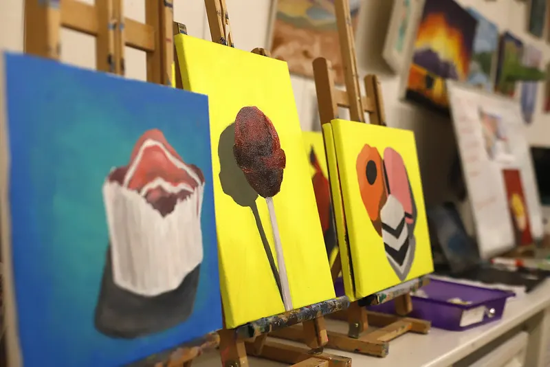 Finished canvas paintings lined up on easels after a painting session