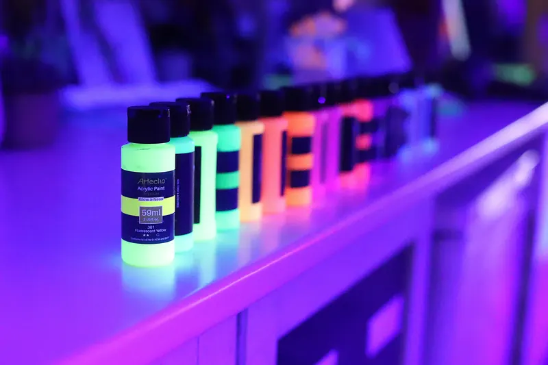 Bottles of fluorescent paint glowing under UV light
