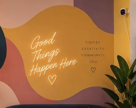 The Pictura neon sign ‘Good Things Happen Here’ on an ochre wall